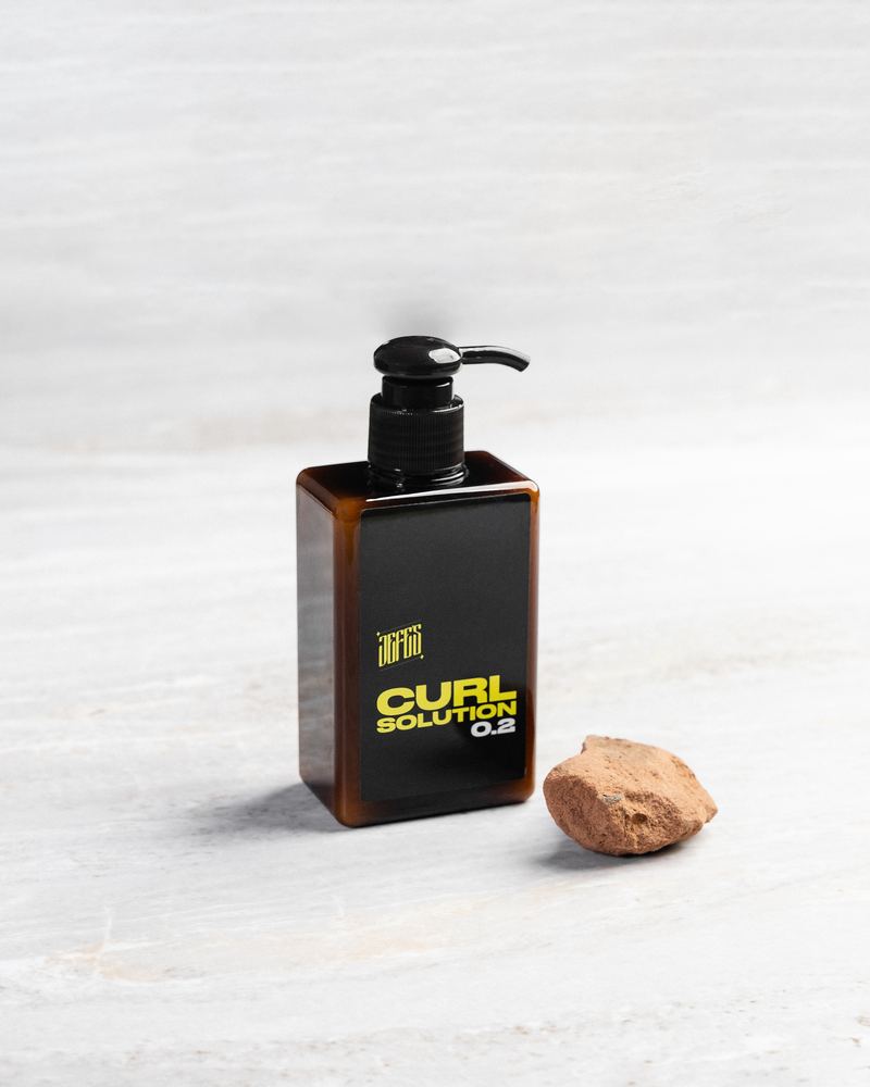 Jefes Curl Solution 0.2 pump bottle on a stone surface